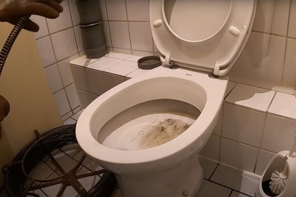 Sanrotech24 aus Berlin Charlottenburg bei der Rohrreinigung eines WC,s mit der mechanischen Spirale